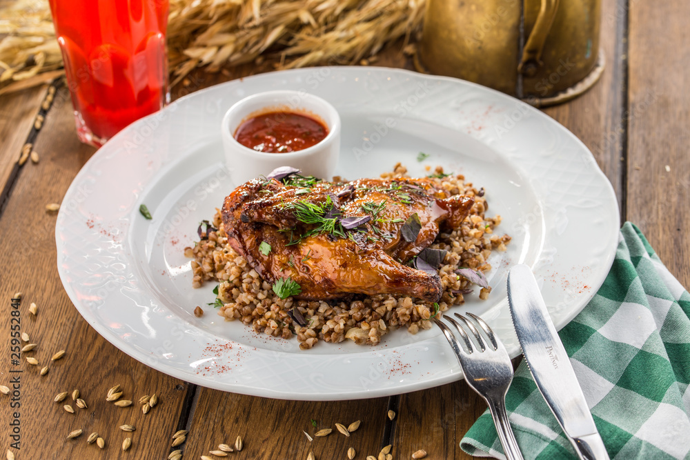 Chicken half with boiled buckwheat and berry drink on wooden table