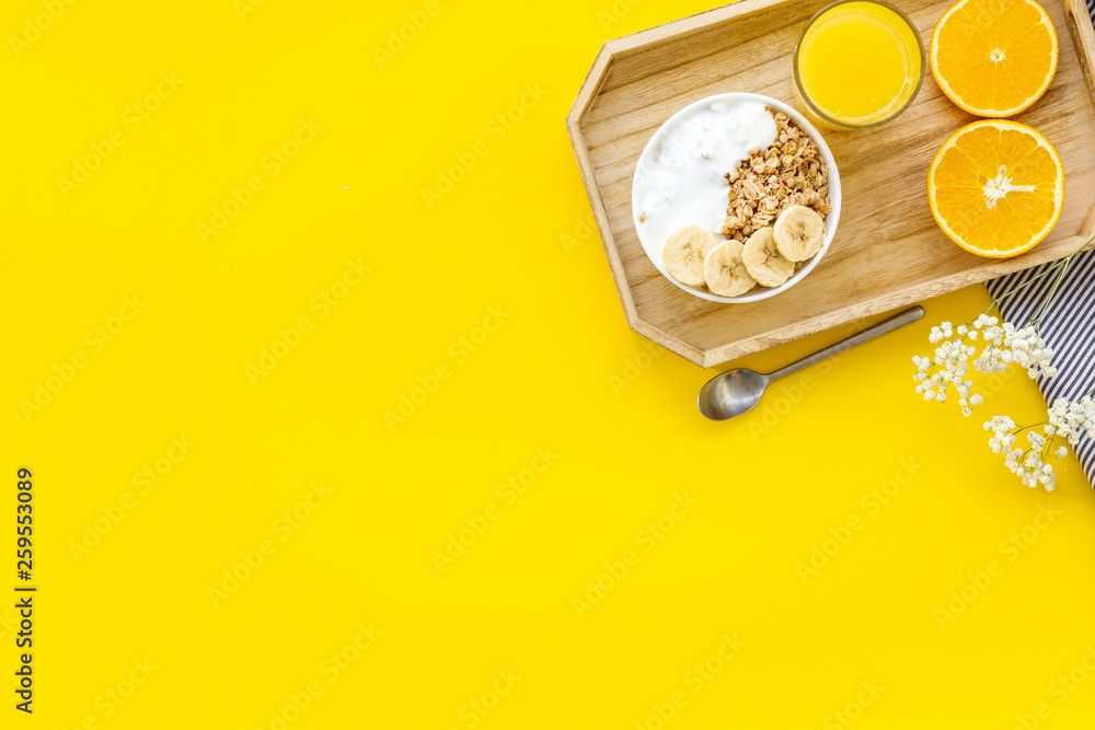 Bright breakfast with granola and orange juice on yellow background top view mockup Bright breakfast with granola and orange juice on yellow background top view mockup