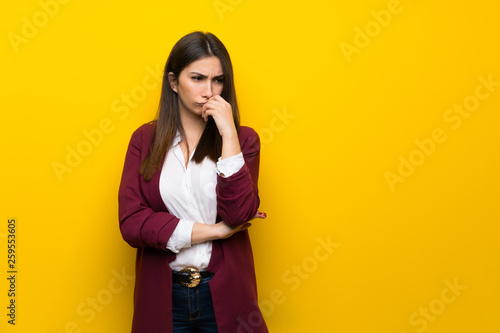 Young woman over yellow wall having doubts © luismolinero
