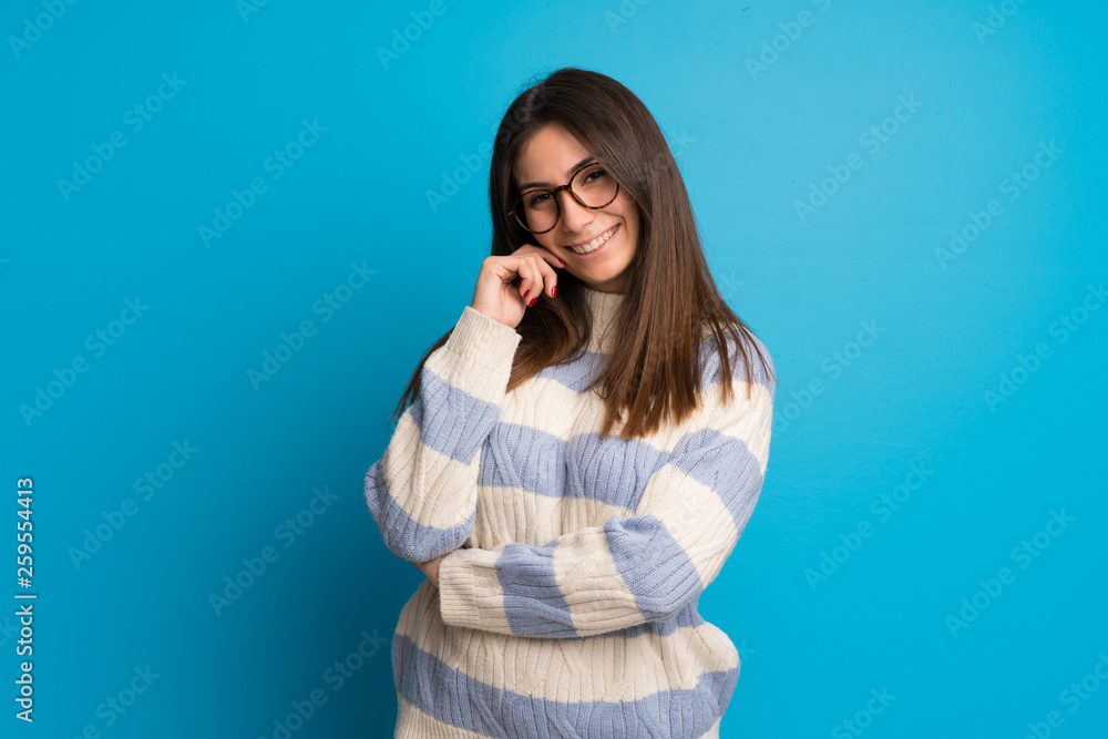 Young woman over blue wall with glasses and smiling Young woman over blue wall with glasses and smiling