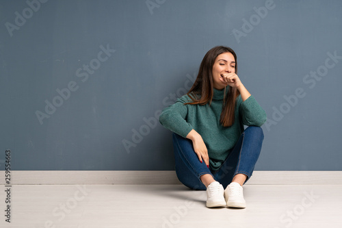 Young woman sitting on the floor is suffering with cough and feeling bad © luismolinero
