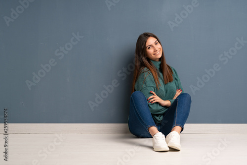 Young woman sitting on the floor with arms crossed and looking forward