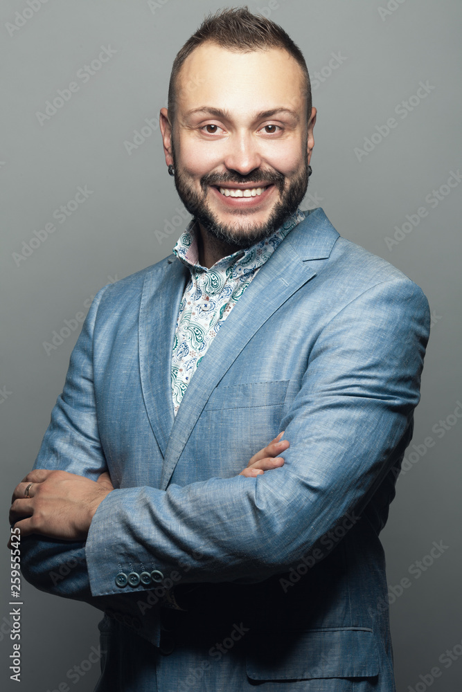 Fototapeta premium Portrait of funny smiling man working as anchorman, standing and posing against gray background. Studio shot