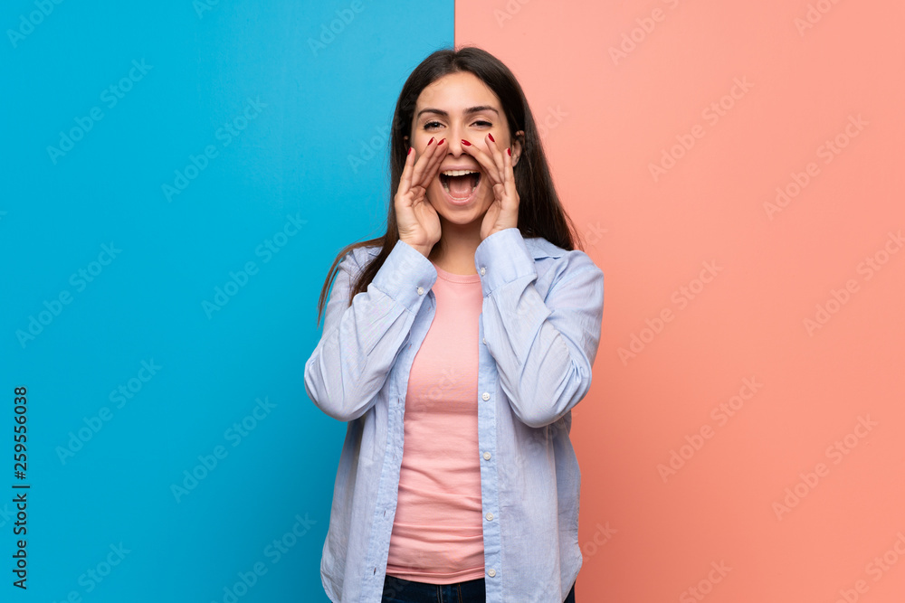 Young woman over pink and blue wall shouting and announcing something Young woman over pink and blue wall shouting and announcing something