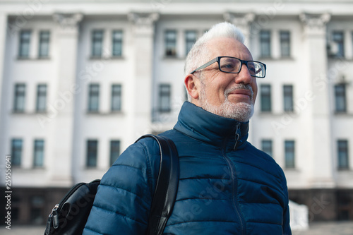 Active retirement concept. Portrait of handsome silver haired mature man watching signtseeing attractions in center of old European capital city. Nice winter day. Modern haircut, beard. Outdoor shot photo