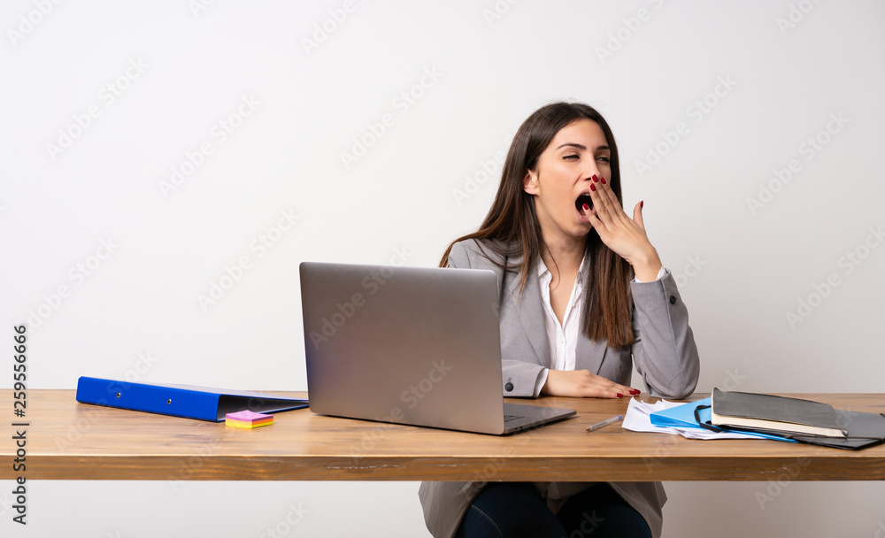 Business woman in a office yawning and covering wide open mouth with hand Business woman in a office yawning and covering wide open mouth with hand