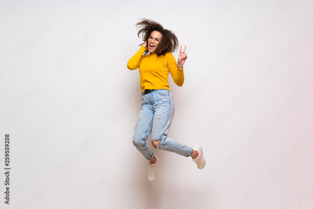 Dominican woman with curly hair jumping over isolated white background Dominican woman with curly hair jumping over isolated white background