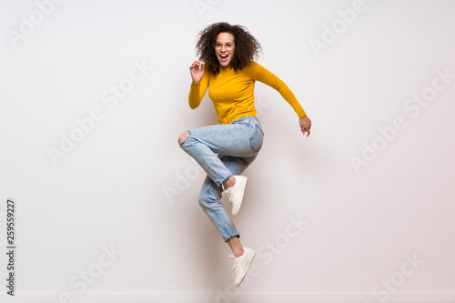 Dominican woman with curly hair jumping over isolated white background
