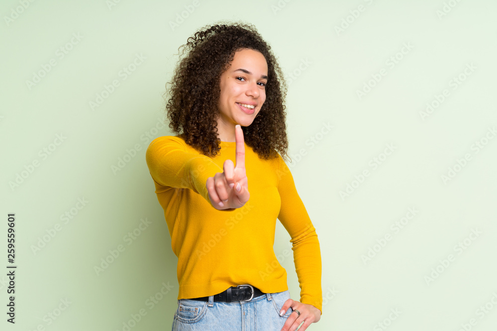 Dominican woman over isolated green background showing and lifting a finger