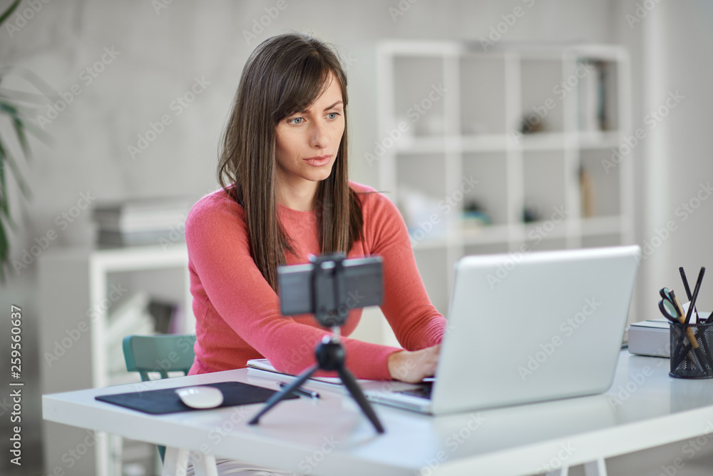 Beautiful serious Caucasian businesswoman sitting in modern office and using laptop. Beautiful serious Caucasian businesswoman sitting in modern office and using laptop.
