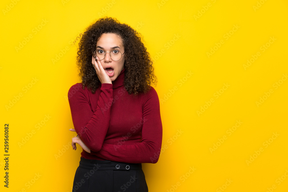 Dominican woman with turtleneck sweater surprised and shocked while looking right Dominican woman with turtleneck sweater surprised and shocked while looking right