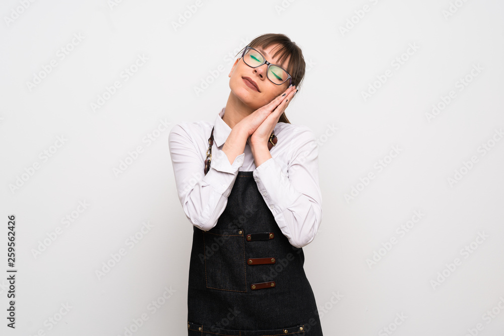 Young woman with apron making sleep gesture in dorable expression Young woman with apron making sleep gesture in dorable expression