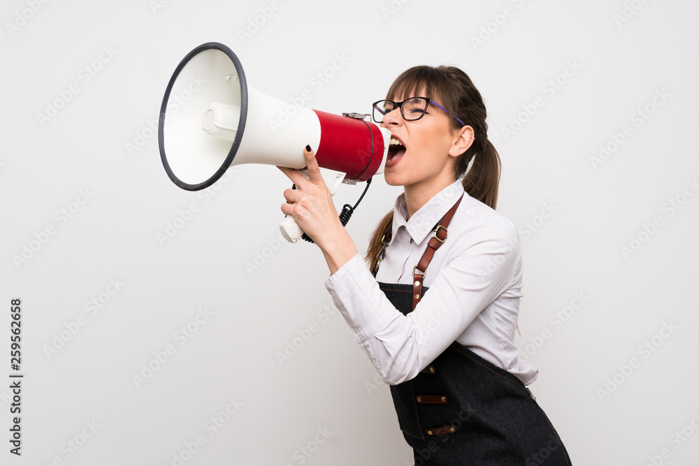 Young woman with apron shouting through a megaphone Young woman with apron shouting through a megaphone