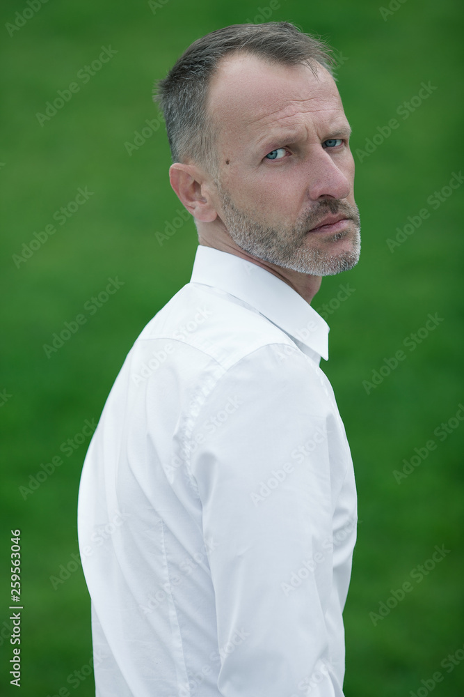 Fabulous at any age. Portrait of 45-year-old man standing over green grass background  in white shirt. Close up. Classic style. Gray hair. Outdoor shot Stock  Photo | Adobe Stock