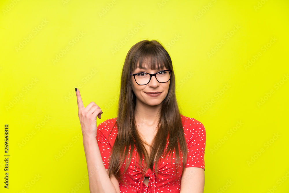 Young woman over green wall pointing with the index finger a great idea Young woman over green wall pointing with the index finger a great idea