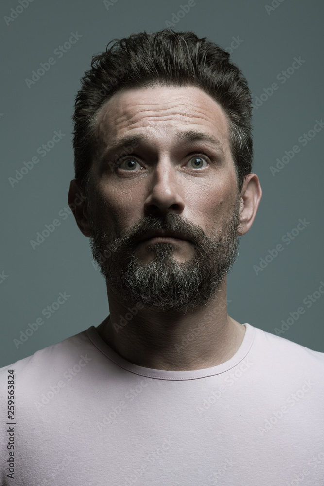 Obraz premium Fabulous at any age. Portrait of shocked 40-year-old man standing over dark gray background. Close up. Classic style. Scar on forehead. Studio shot