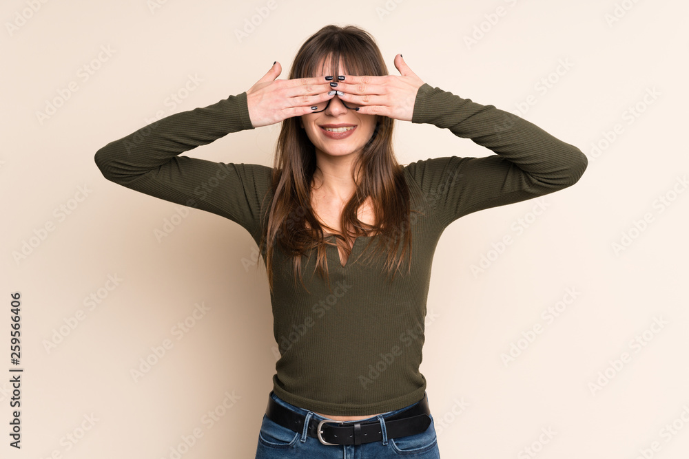 Young woman on ocher background covering eyes by hands Young woman on ocher background covering eyes by hands
