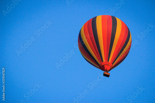 Striped multicolored balloon in a bright blue sky.