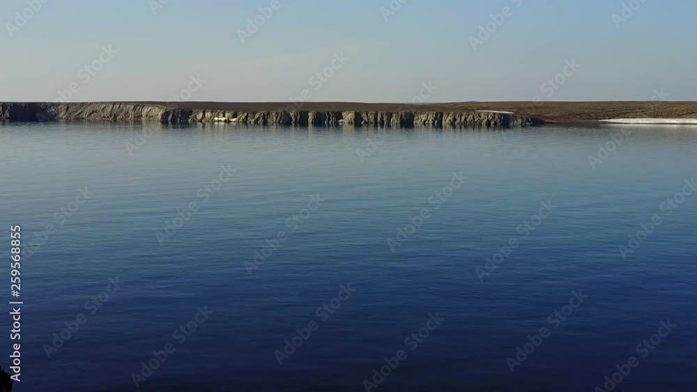Stone in water and coastline of Arctic Ocean in summer on desert Novaya Zemlya and lonely abandoned world of wildlife and nature of quiet north. Stone in water and coastline of Arctic Ocean in summer on desert Novaya Zemlya and lonely abandoned world of wildlife and nature of quiet north.