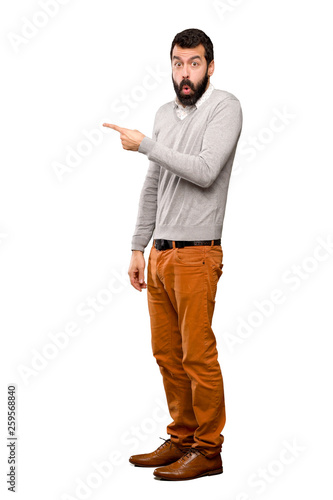 Handsome man surprised and pointing side over isolated white background