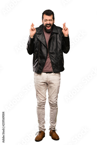 Handsome man with beard with fingers crossing over isolated white background