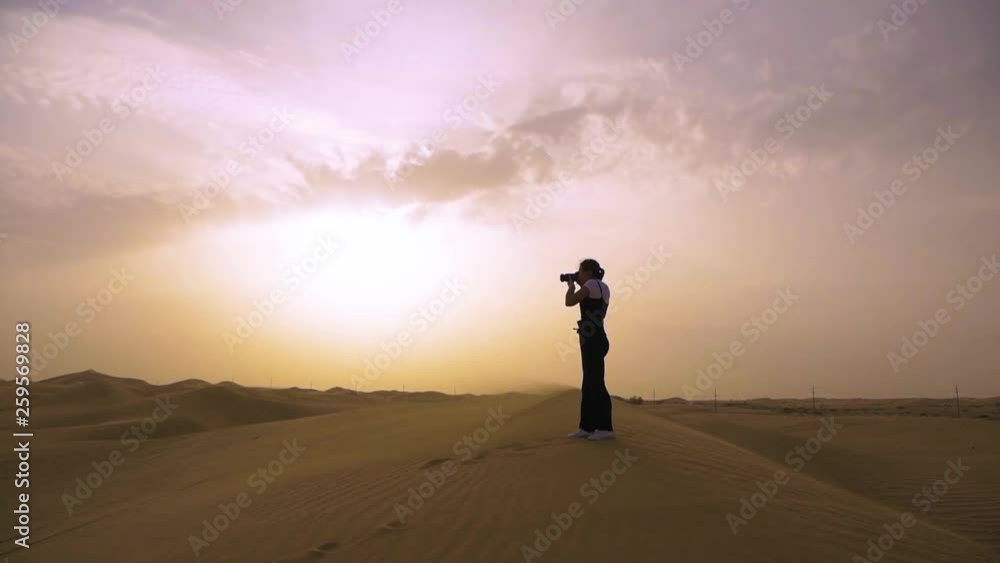 A Professional Photographer Shoots a Landscape on Sand Dunes, in the Face of a Dust Storm