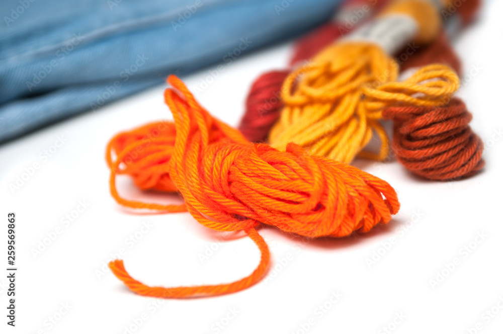 closeup of orange  cotton threads on white table on blue jeans background