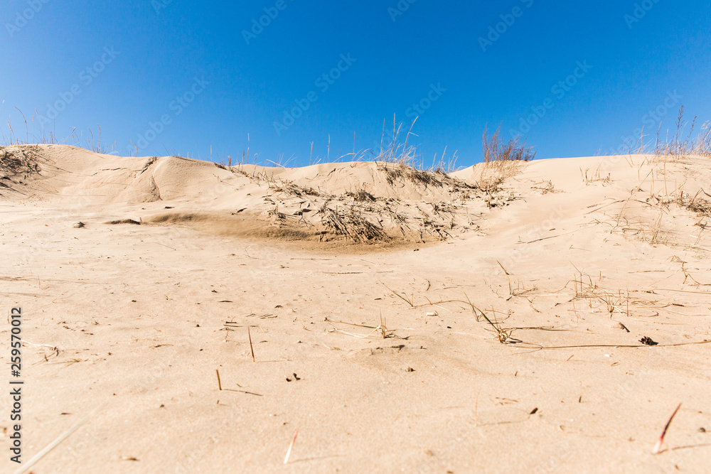 Mountains of yellow sand on the coastline on blue sky background. Beautiful landscape Mountains of yellow sand on the coastline on blue sky background. Beautiful landscape