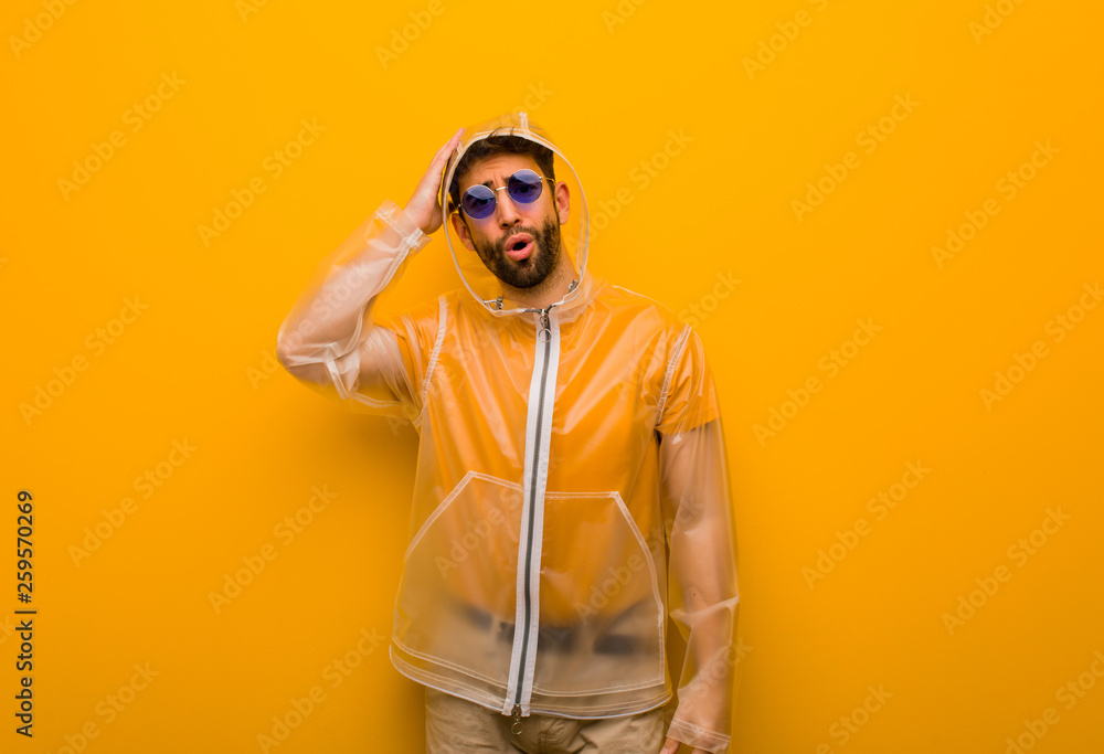 Young man wearing a rain coat worried and overwhelmed Young man wearing a rain coat worried and overwhelmed