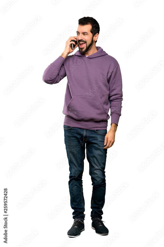 Full-length shot of Handsome man with sweatshirt keeping a conversation with the mobile phone over isolated white background Full-length shot of Handsome man with sweatshirt keeping a conversation with the mobile phone over isolated white background