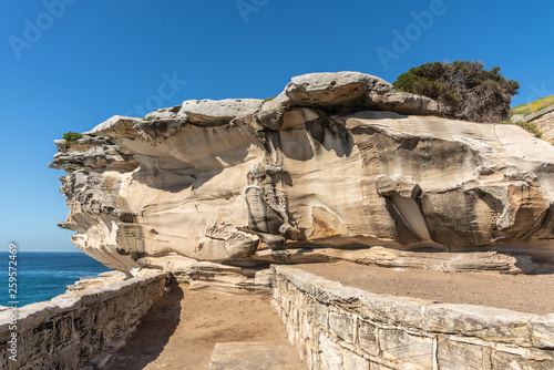 Sydney, Australia - February 11, 2019: Mackenzies Point beige rock formation on South shore lands end of Bondi beach. Blue water and blue sky. photo