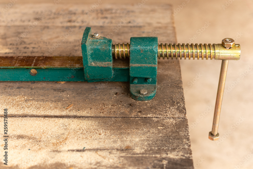 Workpiece clamp, Metal table vise clamp on the wood table. Copy space for text. Workpiece clamp, Metal table vise clamp on the wood table. Copy space for text.