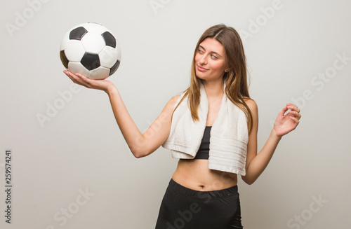 Young fitness russian woman making the gesture of a spyglass. Holding a soccer ball. © Asier