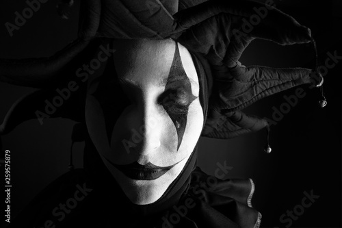 Sad crying jester, black and white photo, close-up.