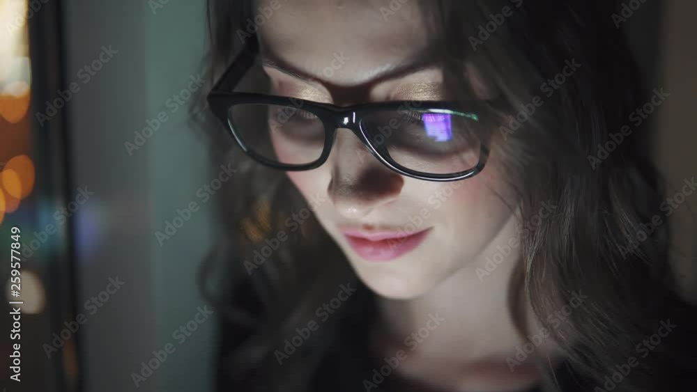 reflection of the screen with glasses. girl uses a smartphone in the dark. portrait of a young woman on the background of the night city reflection of the screen with glasses. girl uses a smartphone in the dark. portrait of a young woman on the background of the night city