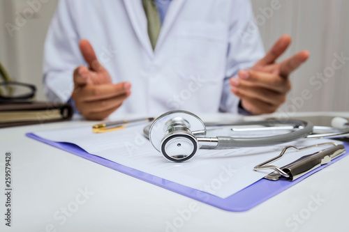Close-up of stethoscope is lying on the clipboard in front of  a doctor.