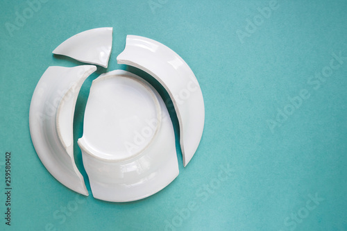 broken white plate on green background, copy space, top view