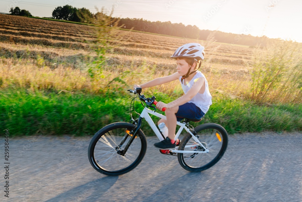 Boy in white helmet riding his bicycle. Boy in white helmet riding his bicycle.