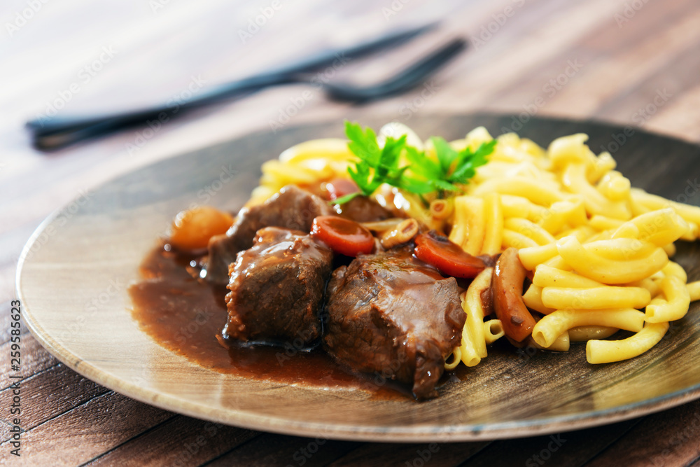 close-up of plate of pasta and pork with lettuce