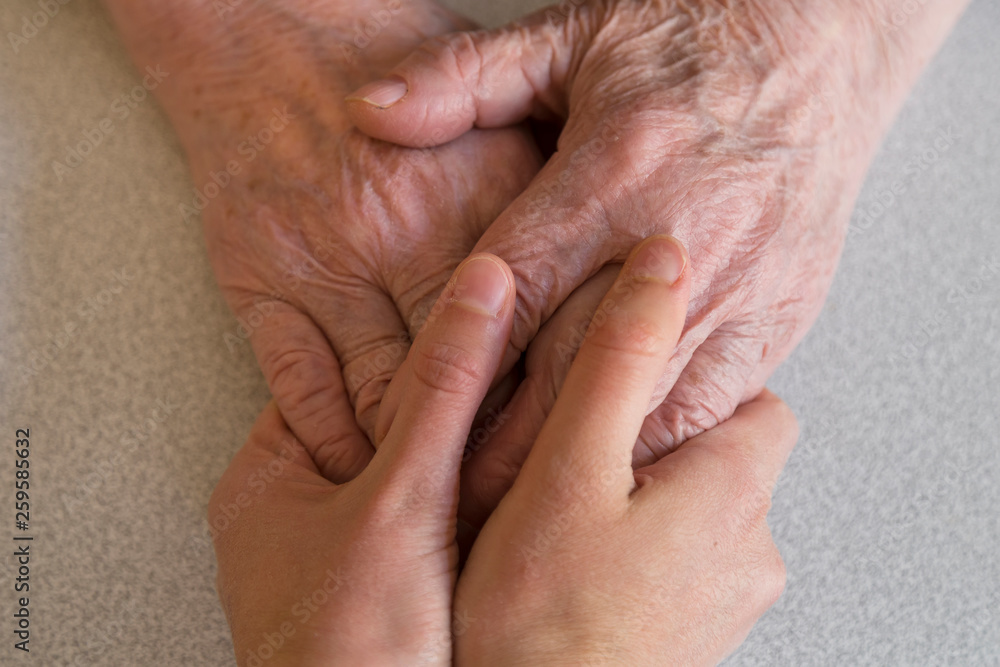 old woman wrinkled and young hands on the background.