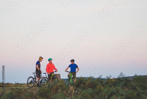 Mountain Bike Riding Friends on Hill at Sunset