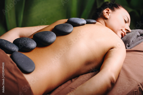Hot vulcanic stones on a young female back while doing hot vulcaninc theraphy in a spa center.