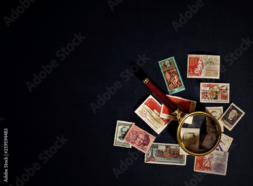 old Soviet stamps,tweezers and magnifying glass on a dark background