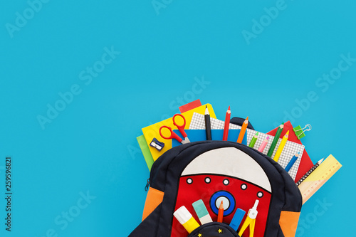 Bagpack with school supplies. Back to shool concept. Rocket rucksack with books and stationery. Top view and copy space. photo