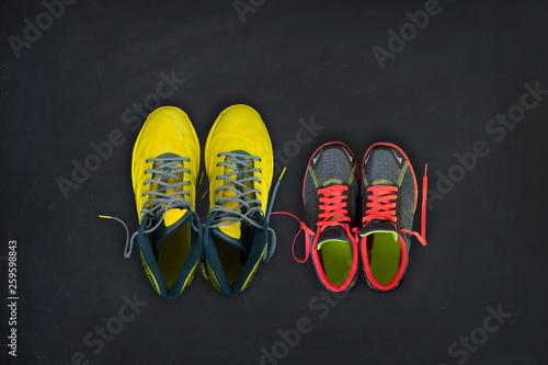 Fitness sneakers for him and for her on a black background. Concept of healthy lifestyle, sport and activity. Flat lay composition.