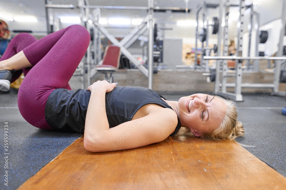 Φωτογραφία Tired and exhausted woman in gym, lying on the floor, having rest after fitness workout