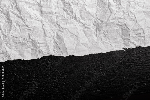 White crumpled paper against a wall in black. View from above