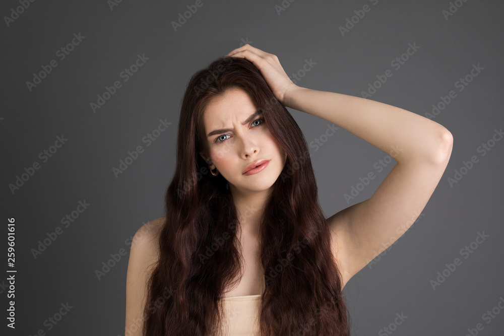 Portrait of displeased young brunette girl touching hair Portrait of displeased young brunette girl touching hair