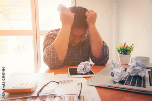 business, people, paperwork and deadline concept - stressed businessman with papers and charts sitting at table in office
