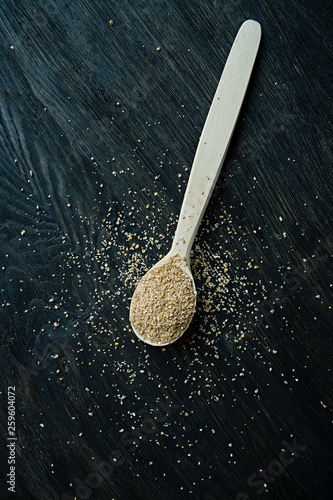 Wheat groats in a wooden spoon on a wooden dark background. Wooden spoon with wheat grains.